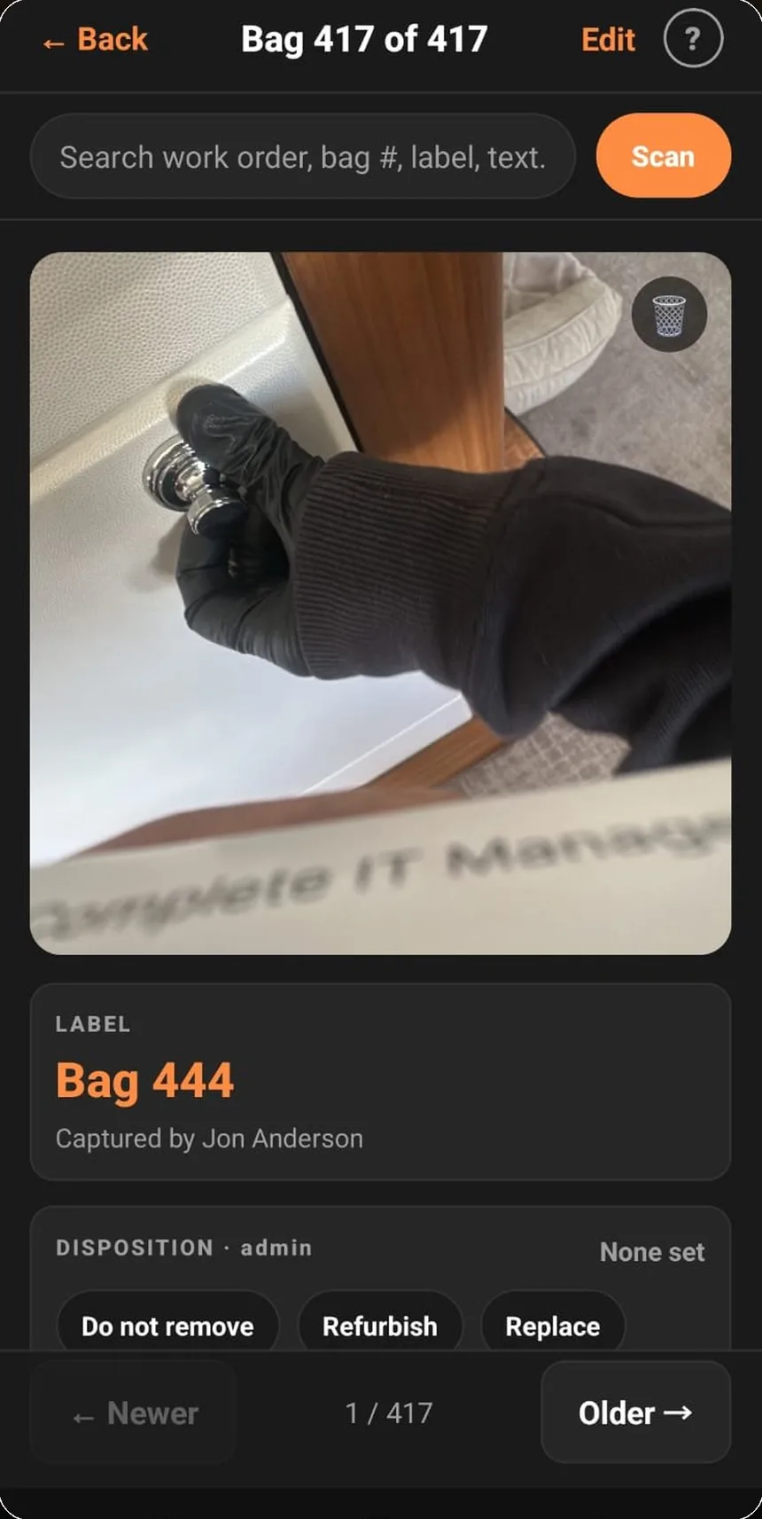 A ReFit capture in progress: a gloved hand holding hardware photographed against the workbench, filed under bag 444.